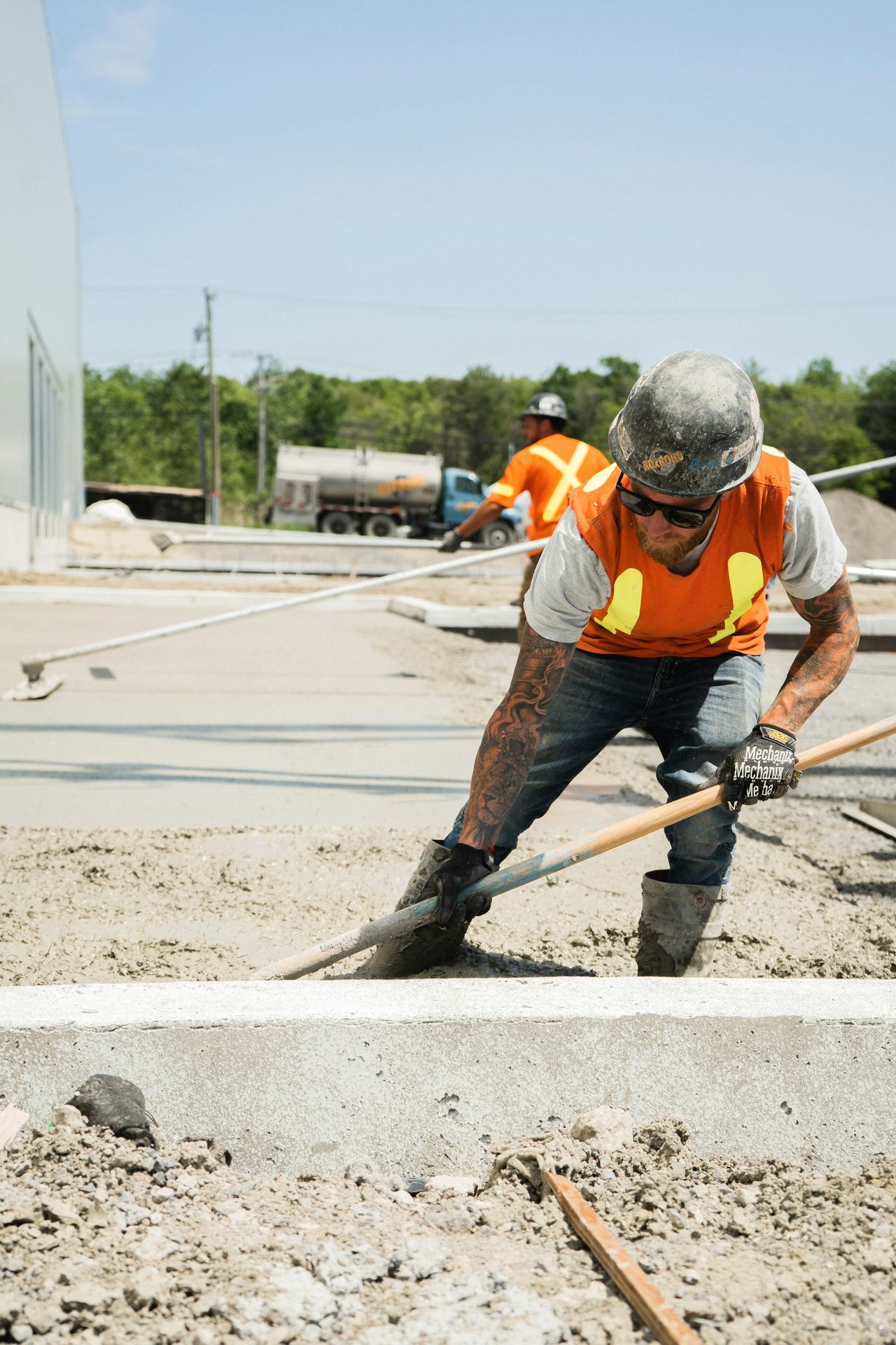 a man in an orange vest is shoveling concrete